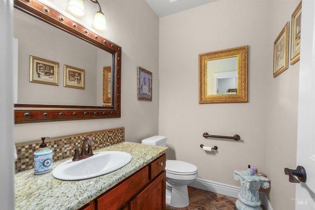 bathroom featuring vanity, backsplash, toilet, and baseboards