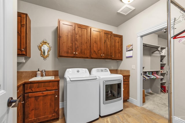 clothes washing area with cabinet space, visible vents, baseboards, washer and dryer, and a sink