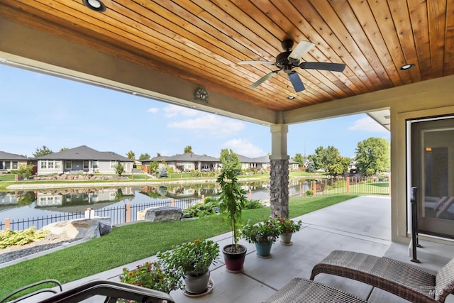 view of patio / terrace with a water view, a residential view, a ceiling fan, and fence