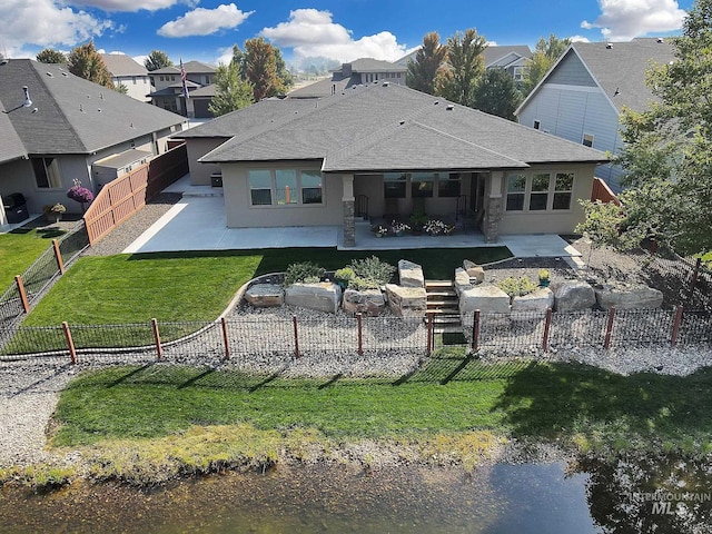 back of property with a lawn, a fenced backyard, a residential view, roof with shingles, and a patio area