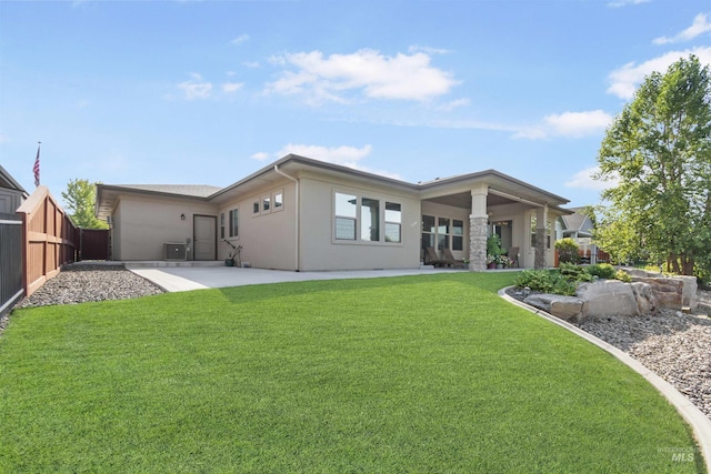 rear view of house with a yard, a patio area, fence, and stucco siding