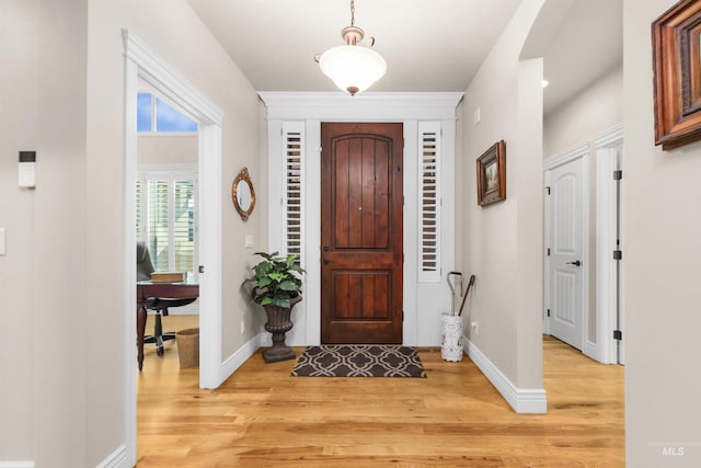 foyer entrance with light wood-style flooring and baseboards