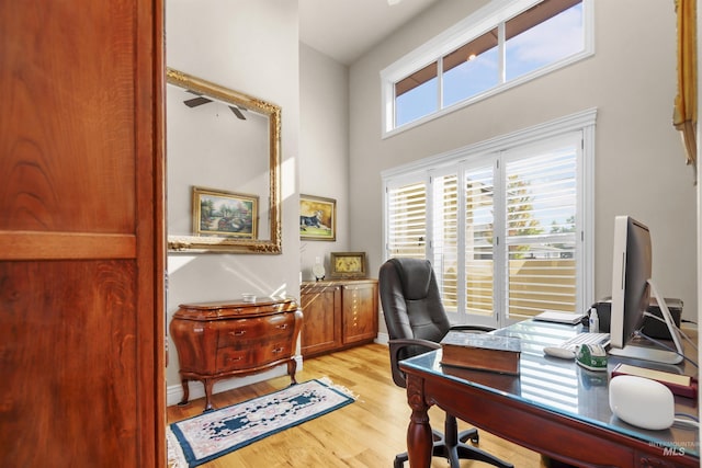 home office featuring a high ceiling, light wood-type flooring, and baseboards