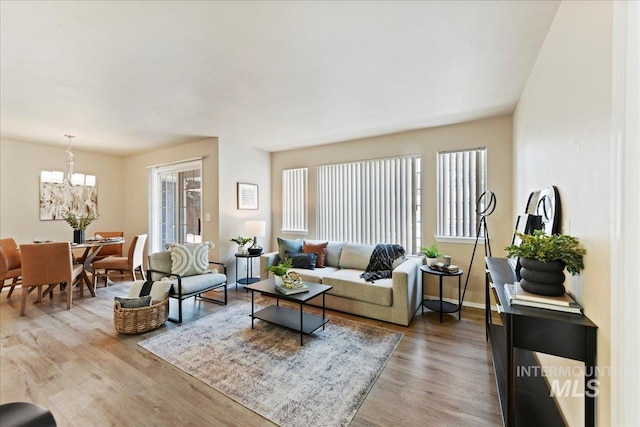 living area with baseboards, a chandelier, and wood finished floors