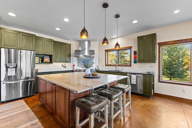 kitchen with a center island, wall chimney range hood, hanging light fixtures, light stone counters, and stainless steel appliances