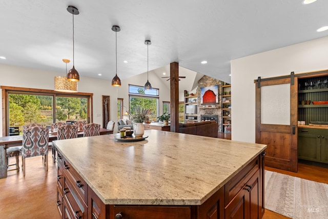 kitchen featuring a center island, a barn door, pendant lighting, vaulted ceiling, and a fireplace