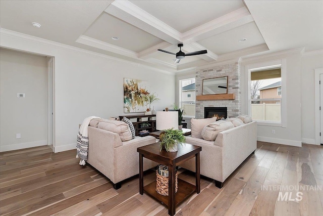 living room with ceiling fan, a large fireplace, coffered ceiling, beamed ceiling, and ornamental molding