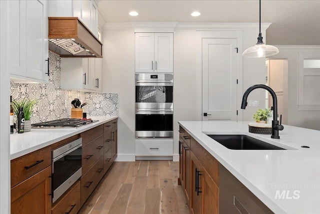 kitchen with stainless steel appliances, white cabinetry, sink, and pendant lighting