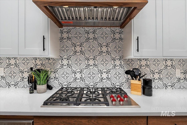 kitchen featuring decorative backsplash, white cabinetry, stainless steel gas cooktop, and custom exhaust hood