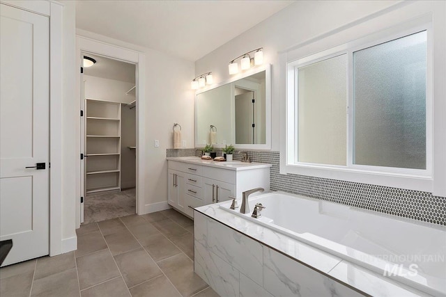 bathroom with tile patterned floors, vanity, and a relaxing tiled tub