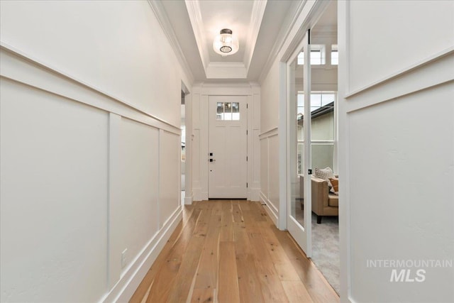 doorway to outside featuring a tray ceiling and light hardwood / wood-style flooring