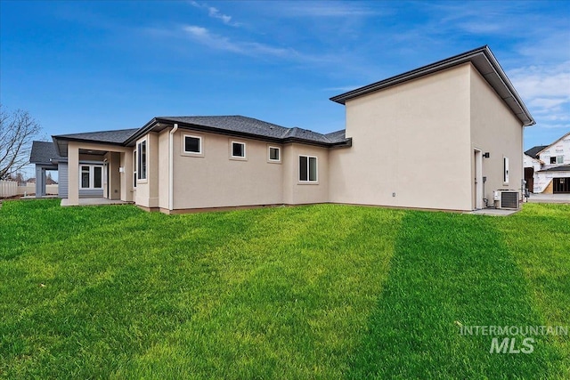 rear view of house featuring cooling unit and a lawn