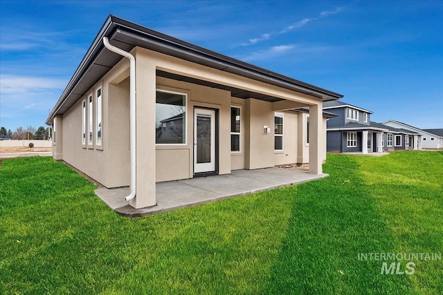 rear view of property featuring a lawn and a patio area