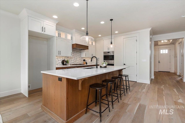 kitchen featuring decorative backsplash, sink, white cabinetry, hanging light fixtures, and a large island