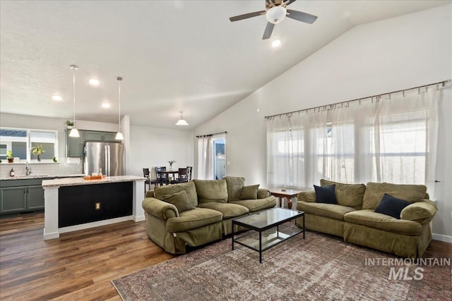 living room featuring lofted ceiling, dark hardwood / wood-style floors, sink, and a wealth of natural light