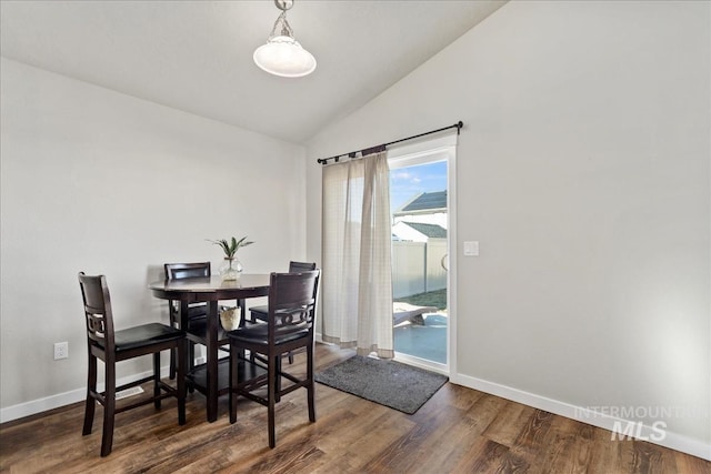 dining space featuring vaulted ceiling and dark hardwood / wood-style flooring