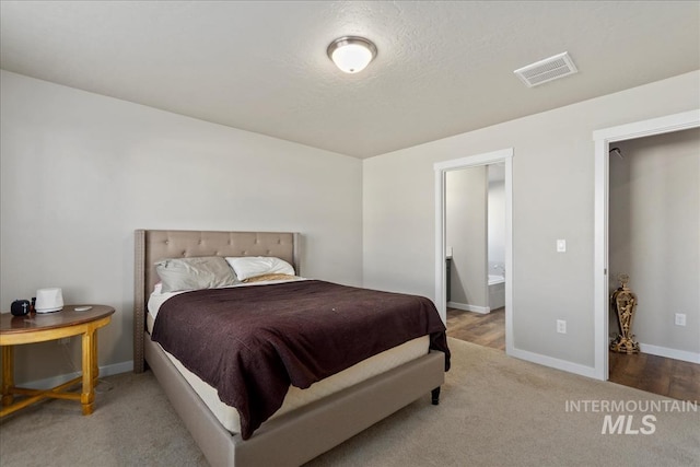 carpeted bedroom featuring connected bathroom and a textured ceiling