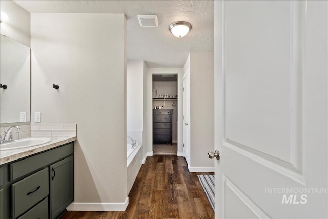 bathroom featuring vanity, hardwood / wood-style floors, a bath, and a textured ceiling