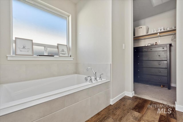 bathroom with hardwood / wood-style flooring and a relaxing tiled tub