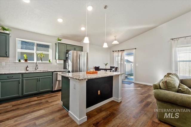 kitchen with sink, decorative light fixtures, vaulted ceiling, a kitchen island, and stainless steel appliances