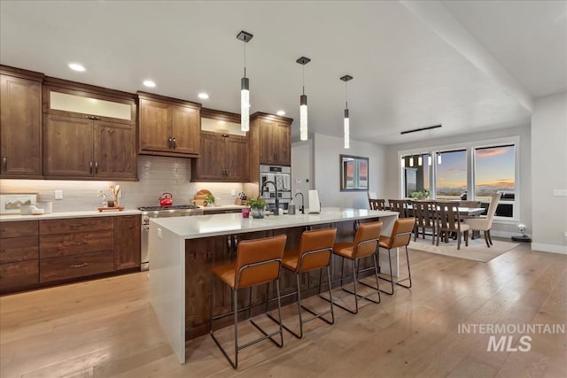 kitchen featuring a breakfast bar, light countertops, light wood-type flooring, and stainless steel appliances