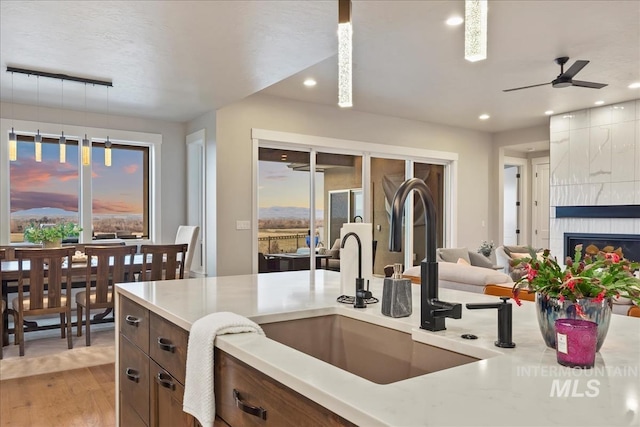 kitchen featuring light wood-type flooring, a ceiling fan, a sink, recessed lighting, and light countertops