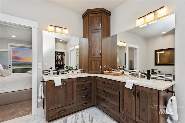 full bathroom featuring double vanity, marble finish floor, ensuite bathroom, and a sink