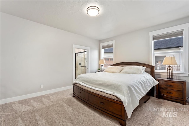 bedroom with baseboards, light carpet, and ensuite bath