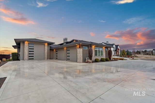 view of front of property with stone siding, an attached garage, concrete driveway, and fence