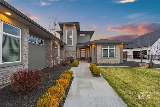 view of front facade featuring a front yard, stone siding, and stucco siding