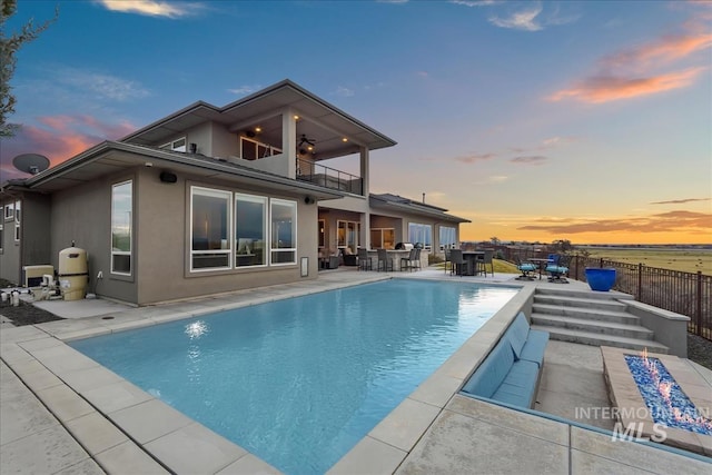 back of property featuring stucco siding, outdoor dining area, a fenced backyard, a balcony, and a patio