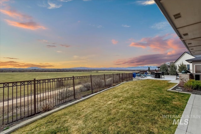 yard at dusk with visible vents, a rural view, and fence