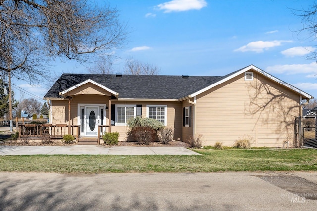 ranch-style house featuring a shingled roof and a front lawn