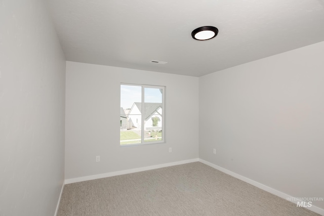 empty room with carpet flooring, visible vents, and baseboards