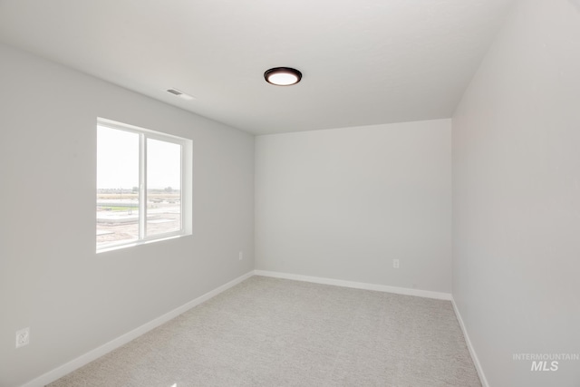 empty room featuring carpet flooring, visible vents, and baseboards