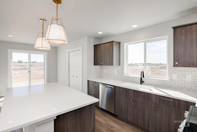 kitchen with light wood finished floors, dishwasher, light countertops, pendant lighting, and a sink