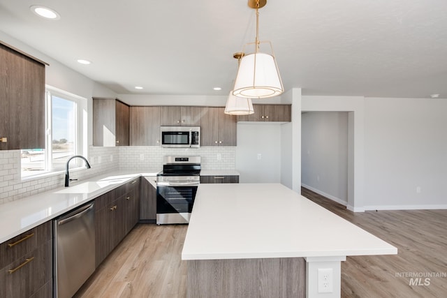 kitchen featuring appliances with stainless steel finishes, light countertops, and decorative light fixtures