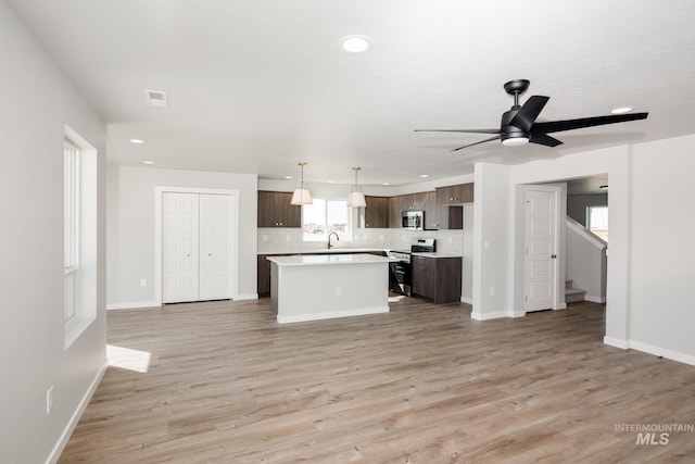 kitchen with light countertops, appliances with stainless steel finishes, dark brown cabinets, a center island, and decorative light fixtures