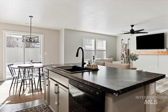 kitchen with dishwasher, wood finished floors, dark countertops, and a sink