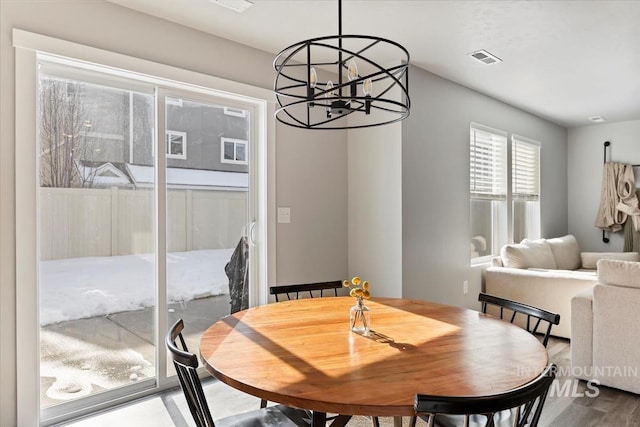 dining area with dark wood-style flooring, visible vents, and an inviting chandelier