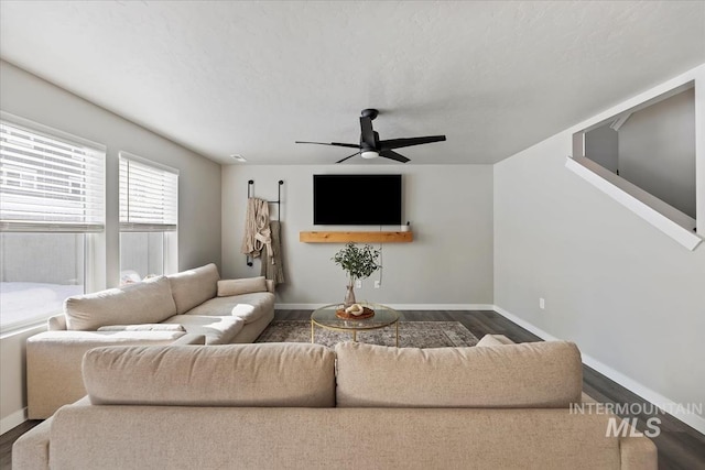 living area with baseboards, a ceiling fan, and wood finished floors