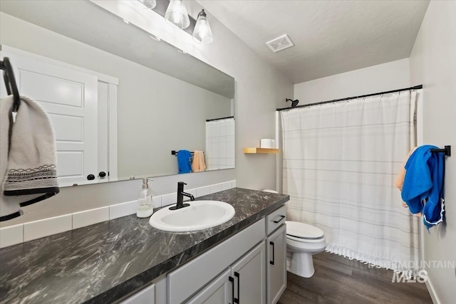 full bathroom featuring visible vents, toilet, wood finished floors, curtained shower, and vanity