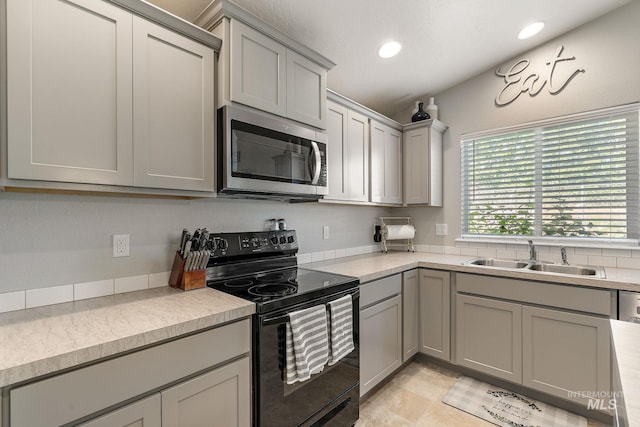 13221 S Clarion River Ave, Nampa, ID 83686 - kitchen with stainless steel microwave, black electric range, a sink, gray cabinets, and light countertops