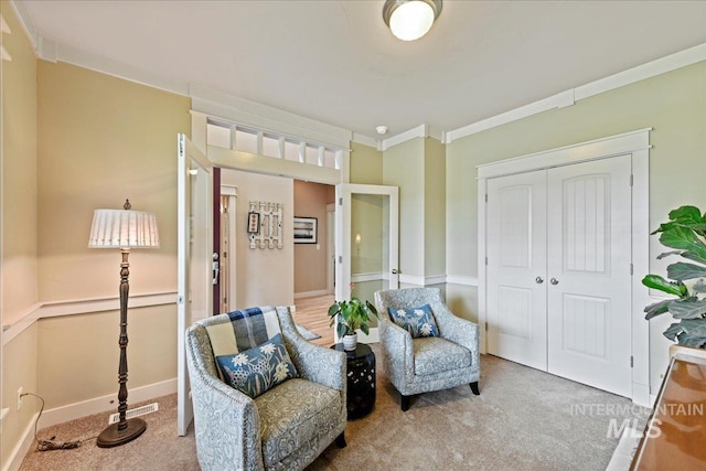 living area with carpet floors, crown molding, visible vents, and baseboards