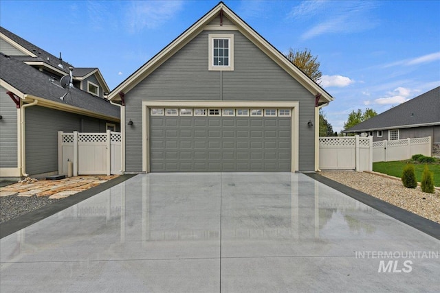 view of front facade with concrete driveway, fence, a gate, and a garage