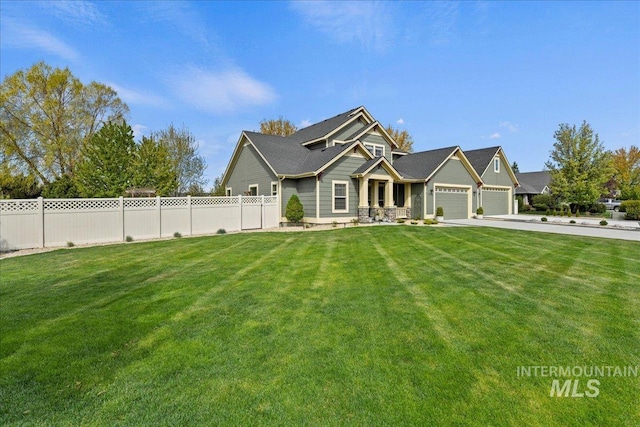 craftsman house with concrete driveway, fence, a front lawn, and a garage