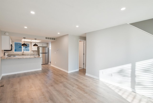 unfurnished living room with sink and light hardwood / wood-style floors