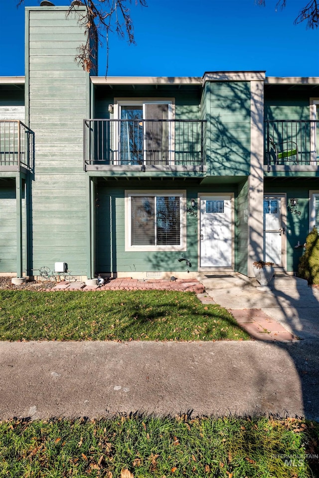 view of front of house with a front lawn and a balcony