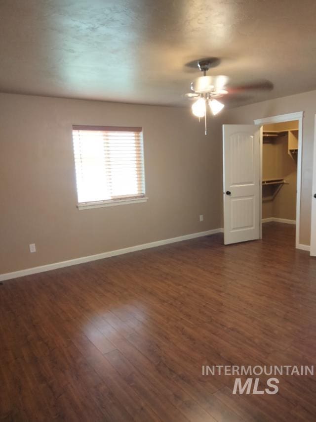 841 Gregory Way, Twin Falls, ID 83301 - unfurnished bedroom with dark wood-style floors, baseboards, a walk in closet, and a ceiling fan