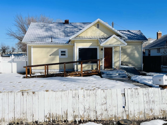 view of front of property featuring metal roof and fence